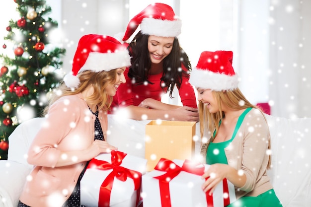 christmas, x-mas, winter, happiness concept - three smiling women in santa helper hats with many gift boxes