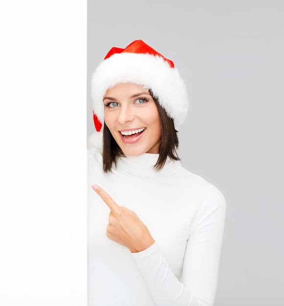 christmas, xmas, holidays and advertisement concept - happy woman in santa helper hat with blank white board