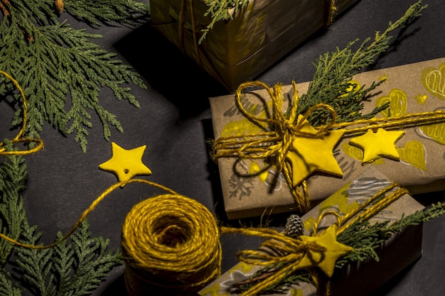 Christmas yellow handmade gift boxes on black background top view. Merry Christmas frame. Winter xmas holiday theme. Happy New Year. Flat lay.