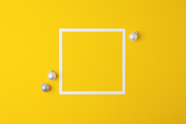 Christmas yellow minimal background with white frame and grey ball flat lay copy space