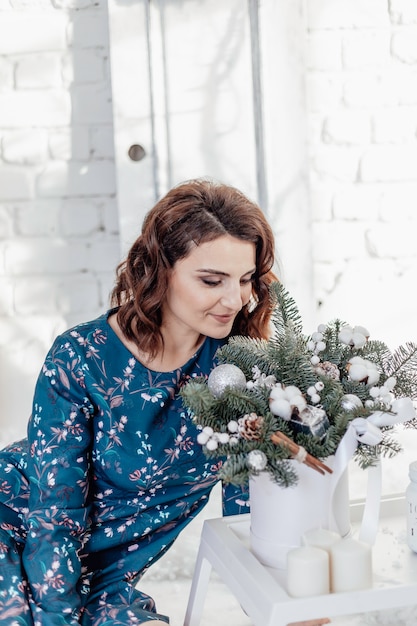 クリスマスの若い女の子は新年の花束に寄りかかった健康な髪型エレガントな女性