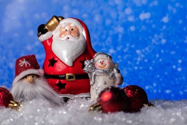 Christmass background ceramic Santa Claus statue,snowman and christmas tree toys standing on snow.