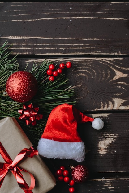 Christmass flatlay geschenkdoos, rood kerstboomspeelgoed, kerstmuts en vuren brance op houten backgro