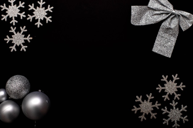 Photo christmass flatlay silvery snowflakes and christmas tree toys on black background.