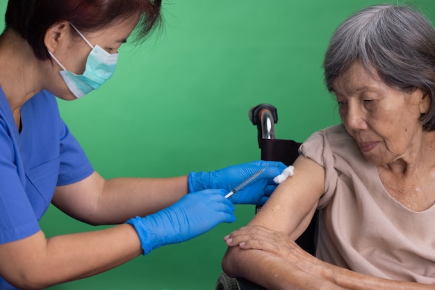 Chroma key, nurse doing vaccine injection to senior woman.