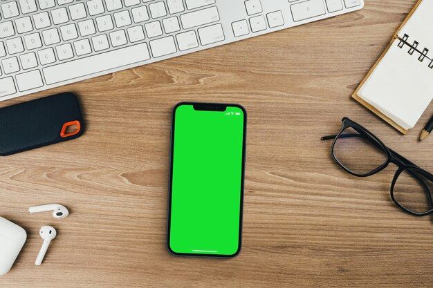 Chroma Key on the smartphone screen on wooden background with a computer beside it. Green screen.