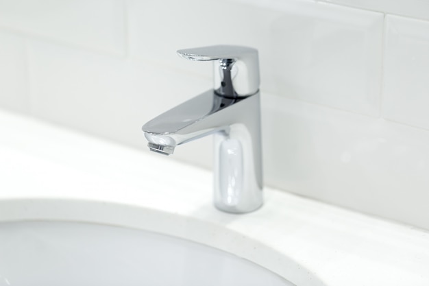 Chrome crane on the ceramic wash basin in the bathroom close up