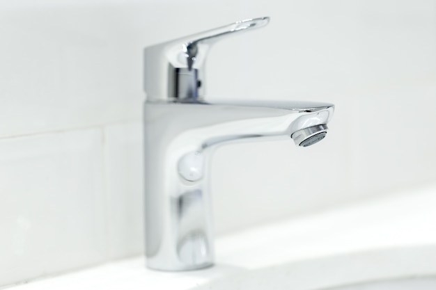 Chrome crane on the ceramic wash basin in the bathroom close up