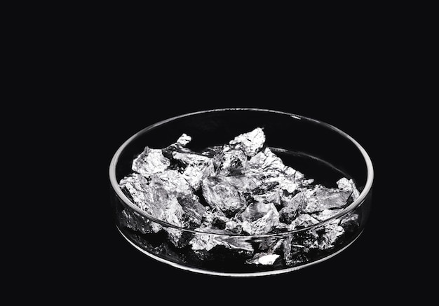 クロムは、ペトリ皿内の黒い背景に分離された産業用鉱石の金属化学元素を断片化します