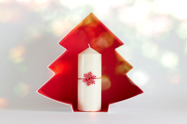 Chrsitmas, New Year composition with white candle, red snowflake and red Christmas tree catboard outline on white background.