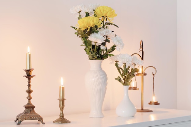 Chrysanten bloemen in vazen en brandende kaarsen op wit interieur