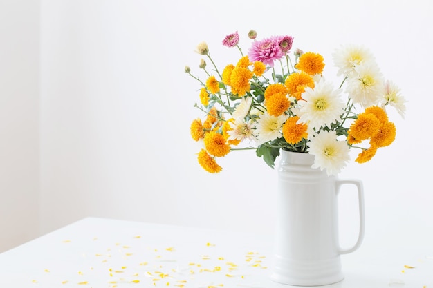 Chrysanthemum bloemen in witte kruik op witte muur als achtergrond