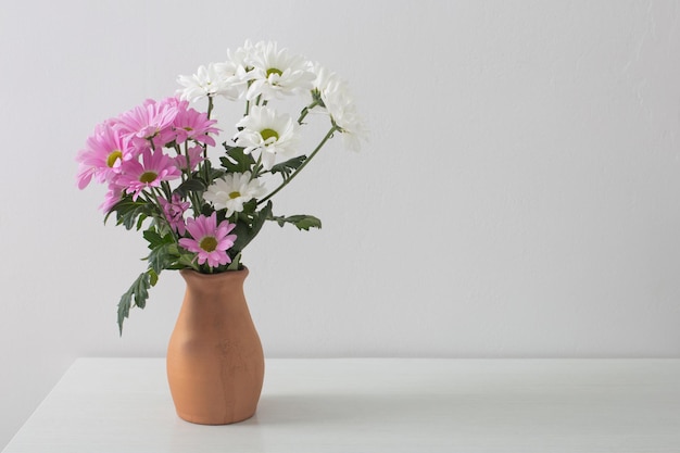 白い背景の上のセラミック花瓶に菊の花