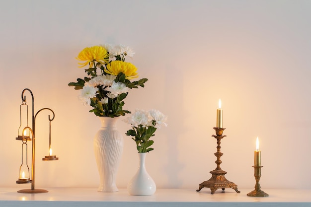 사진 화병에 있는 국화 꽃과 하얀 실내에 촛불을 태우고 있다