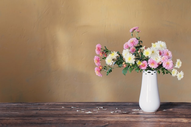 古い木製のテーブルの上に花瓶の菊