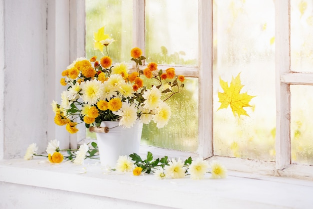 Chrysanthemums in  vase on  windowsill in autumn