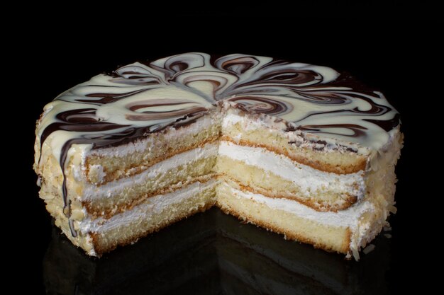 Chunk of chocolate cake decorated with oil cream on a black background