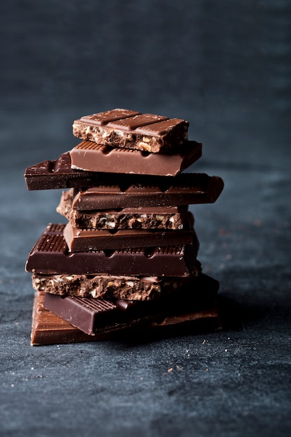 Chunks of broken chocolate stacked on black board.