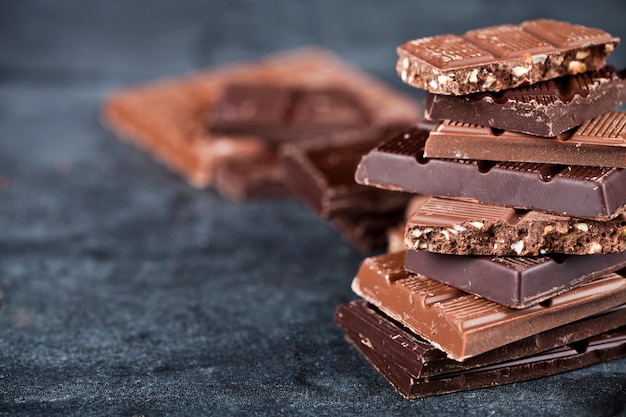 Chunks of broken chocolate stacked on black board.