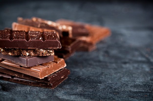 Chunks of broken chocolate stacked on black board. 