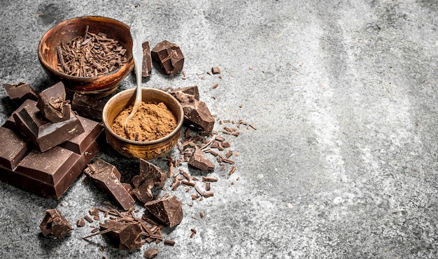 Chunks of chocolate with cocoa powder. On a rustic table.