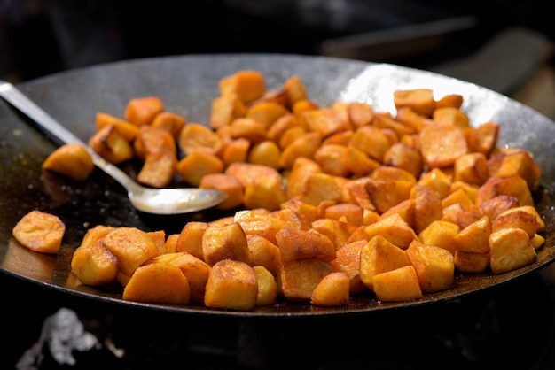 Chunks of fried potatoes in a large skillet during the street food festival