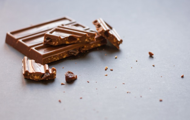 Chunks of milk chocolate with crushed hazelnuts and raisins with alcohol on black backgrou