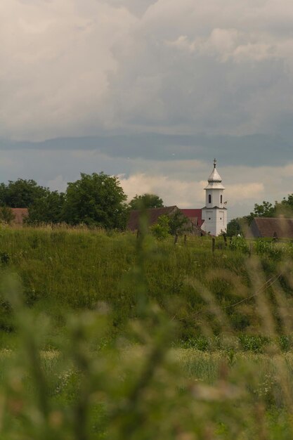 Church by field against cloudy sky