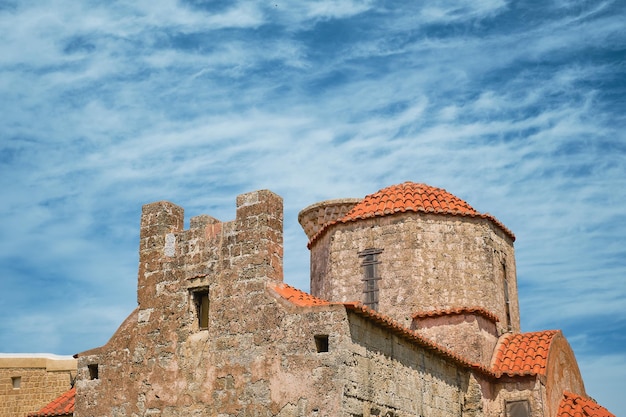 Church of the Holy Trinity against background of sky with clouds streets in the old center of Rhodes Greek islands of the Dodecanese archipelago holidays in Europe and a popular tourist destination