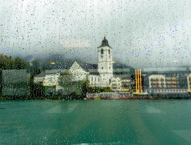 船の窓ガラスの後ろの雨の中の教会