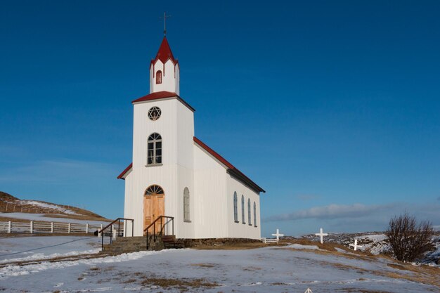 Foto chiesa su un paesaggio coperto di neve contro il cielo durante l'inverno