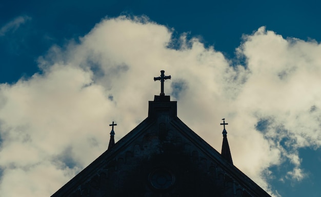 Church tower with crosses silhouetted against cloudy sky