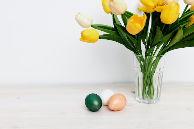 Church traditions Easter eggs and a bouquet of flowers in a vase on a light background