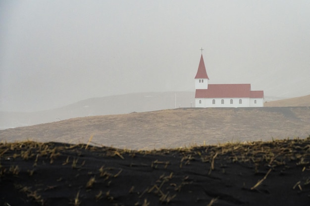 The church of the village of Vik in the South of Iceland seen through the mist