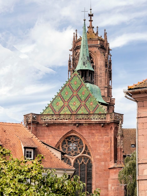 A church with a green roof and a red brick building with a green roof and a tower with a clock on it