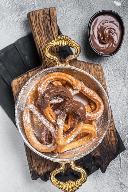 Churros con chocolate typisch Spaanse zoete snack in een koekenpan. Grijze achtergrond. Bovenaanzicht.