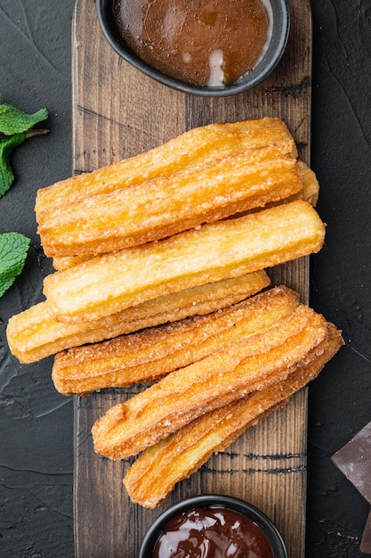 Churros met chocolade, traditionele Spaanse cusine, op zwarte achtergrond, bovenaanzicht plat lag