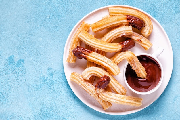 Churros met poedersuiker en chocoladesaus, bovenaanzicht.