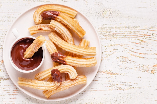 Churros with powdered sugar and chocolate sauce, top view.