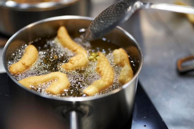 churros worden gebakken in kokende olie in een koekenpan Bevochtig de kokende olie met een spons in de pan