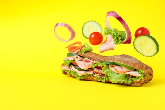 Ciabatta sandwich and ingredients on yellow background