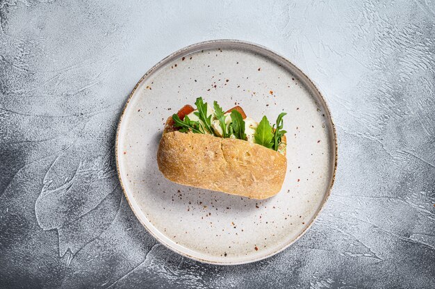 Ciabatta sandwich met verse geitenkaas, perenmarmelade en rucola. Grijs oppervlak. Bovenaanzicht