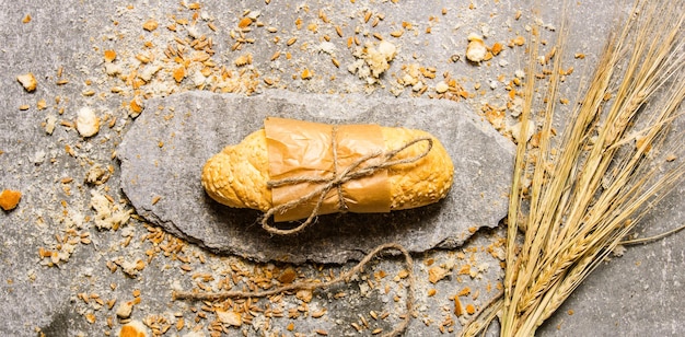 Ciabatta wrapped in paper with crumbs on a stone stand