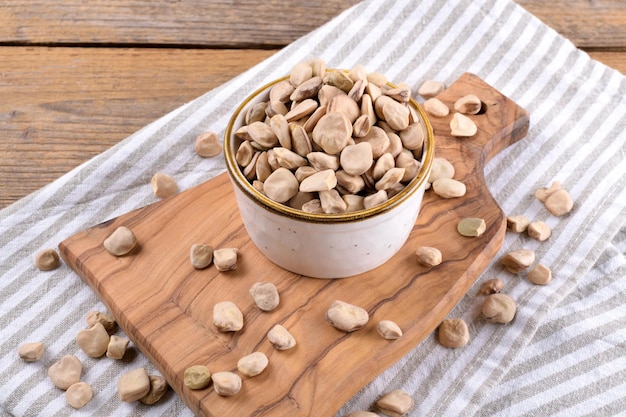 Cicerchia or indian pea on a ceramic bowl with napkin on\
natural wooden background, gluten free food. legumes known as\
lathyrus sativus, chickling vetch, blue sweet pea made in\
puglia