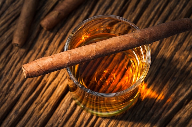 cigar on glass of whisky on old wooden table