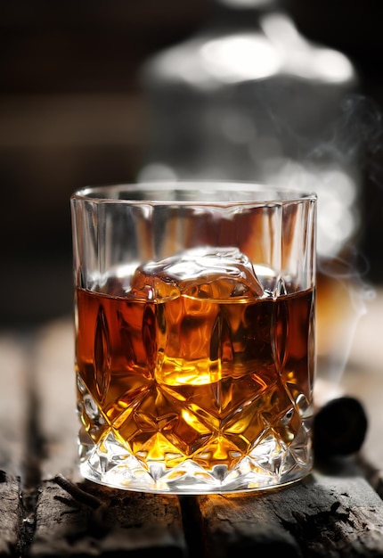 Cigar and glass with whiskey with ice cubes