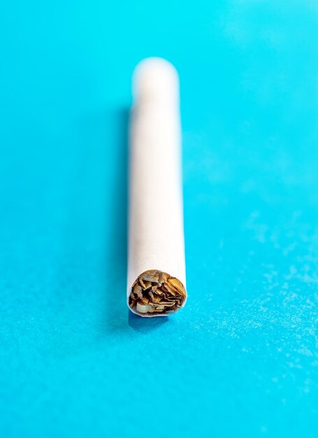 Сигарета на синем фоне крупным планом