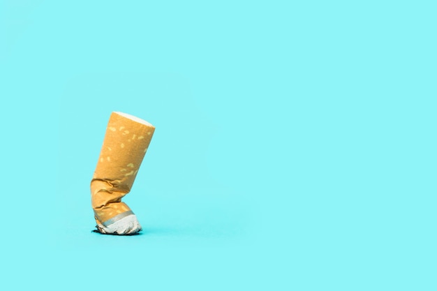 A cigarette butt on a light blue background with copy space