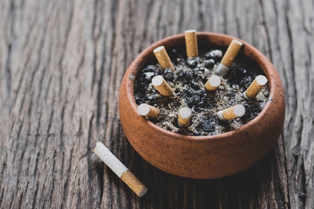 The cigarette butt in the pot is placed on an old wooden floor, World No Tobacco Day concept.