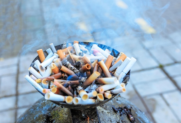 Cigarette butts at ashtray. Close up heap of many smoking cigarettes stubs, cigarette butts in ashtray